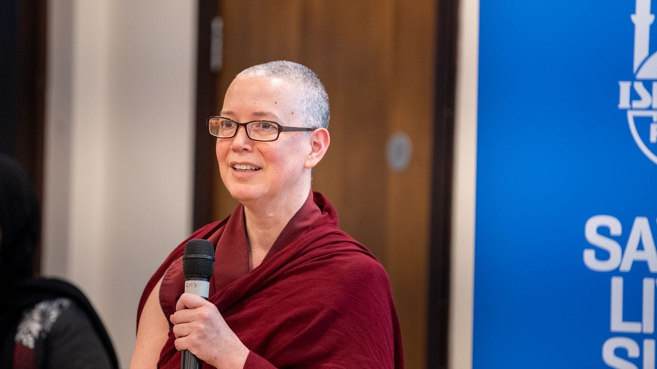 A Buddhist woman is holding a microphone.