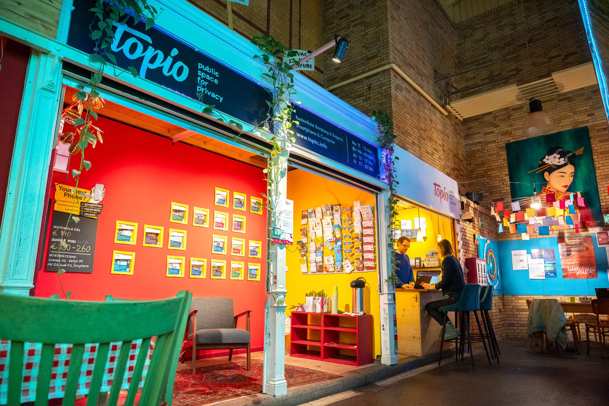 There's a stall with a sign for Topio at the top. Two people sit at the counter.